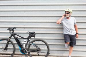 senior man talking on the phone while standing next to his bike