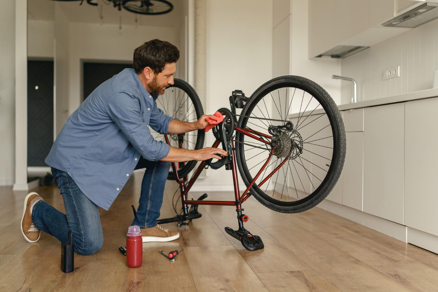 Focused handsome man in casual clothing repairing bicycle itself at home kitchen